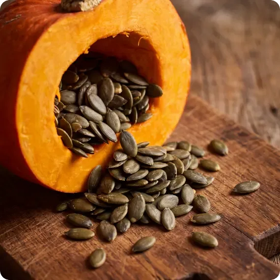 Calabaza abierta con semillas de calabaza sobre una tabla de madera